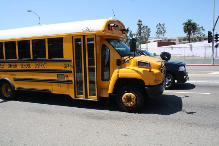 Yellow bus passes the tour bus in Los Angelos.